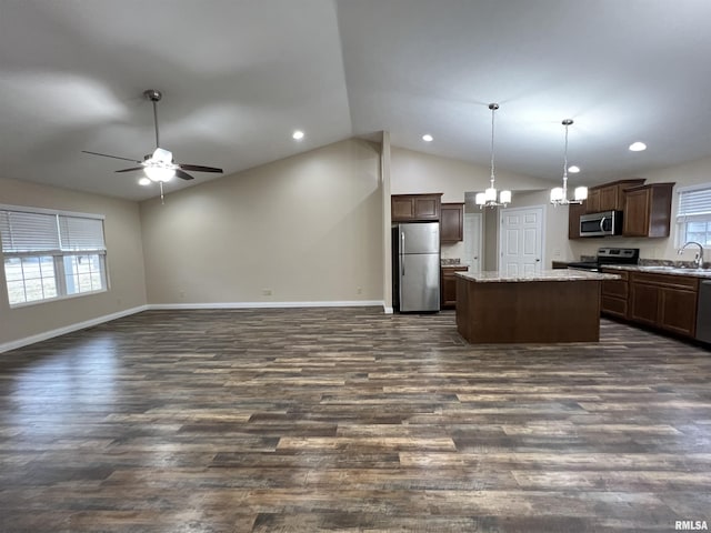 kitchen featuring pendant lighting, appliances with stainless steel finishes, open floor plan, a sink, and a kitchen island