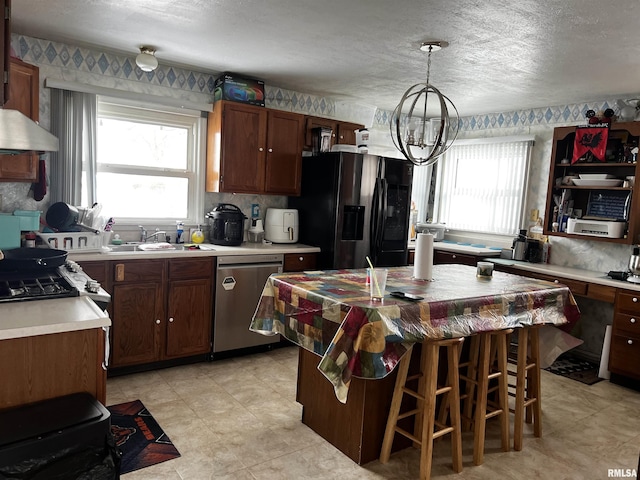 kitchen with fridge with ice dispenser, stainless steel dishwasher, decorative light fixtures, a center island, and sink