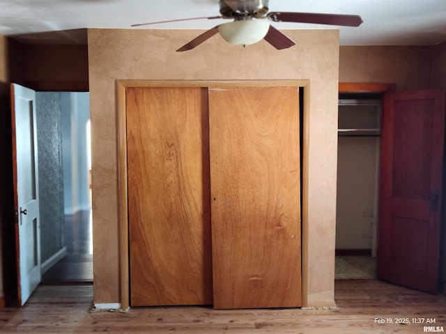 unfurnished bedroom with two closets, ceiling fan, and wood-type flooring