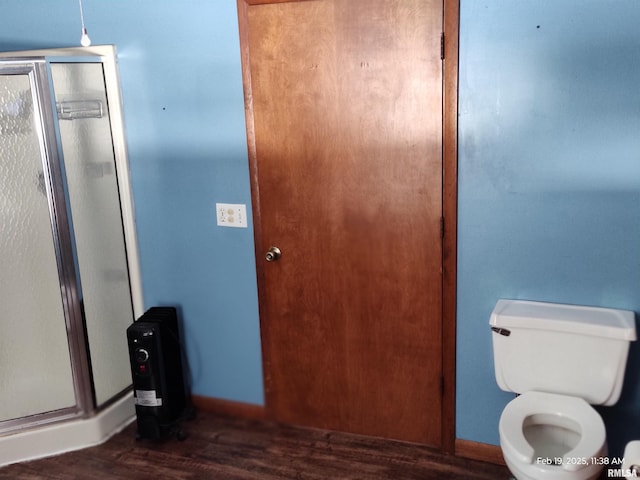 bathroom with hardwood / wood-style floors, an enclosed shower, and toilet