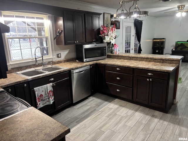 kitchen with appliances with stainless steel finishes, dark brown cabinets, decorative light fixtures, sink, and kitchen peninsula