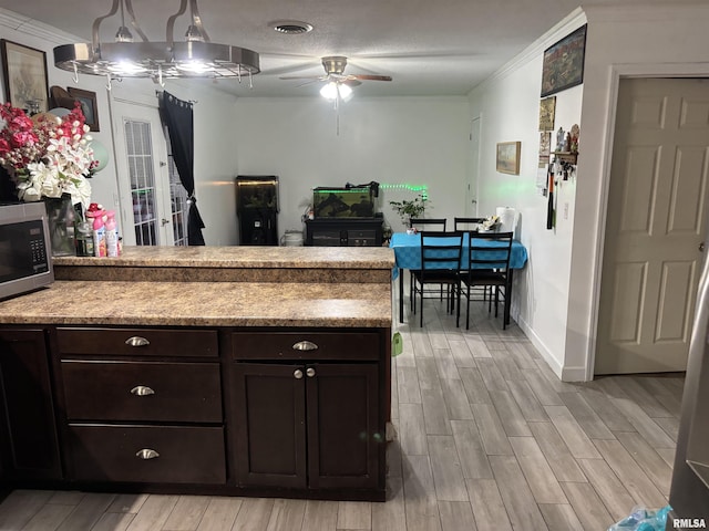 kitchen featuring dark brown cabinets, ceiling fan, ornamental molding, and decorative light fixtures