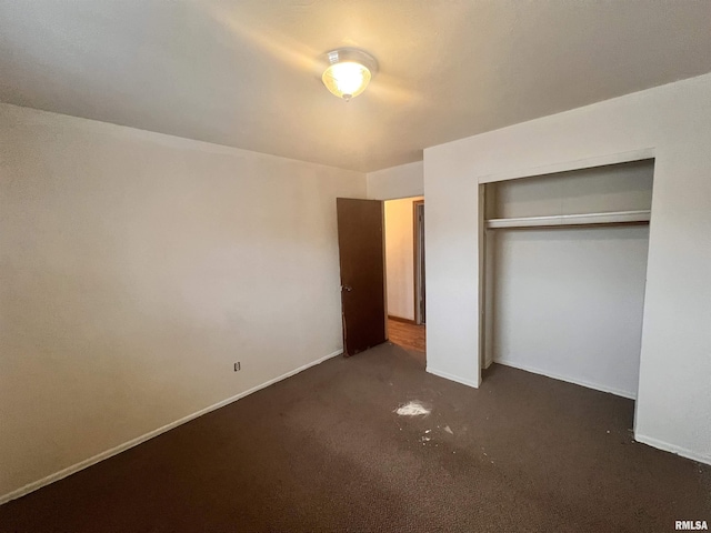 unfurnished bedroom featuring dark carpet and a closet