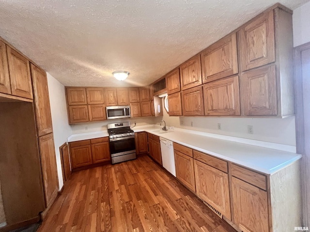 kitchen featuring sink, dark hardwood / wood-style floors, a textured ceiling, and stainless steel appliances