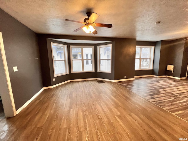 unfurnished living room with hardwood / wood-style flooring, ceiling fan, and a textured ceiling