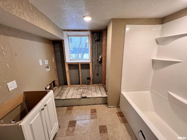 bathroom featuring a textured ceiling and a bathtub