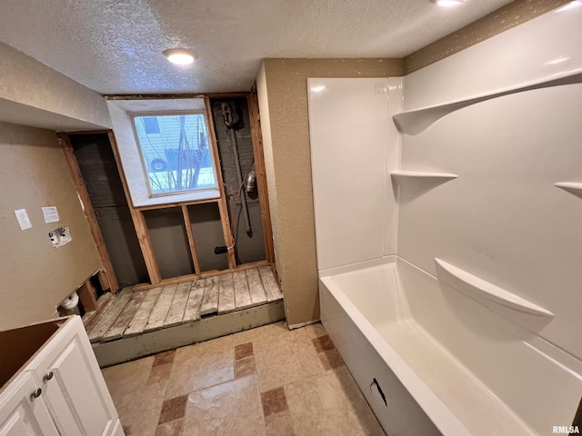 bathroom featuring vanity, a tub to relax in, and a textured ceiling