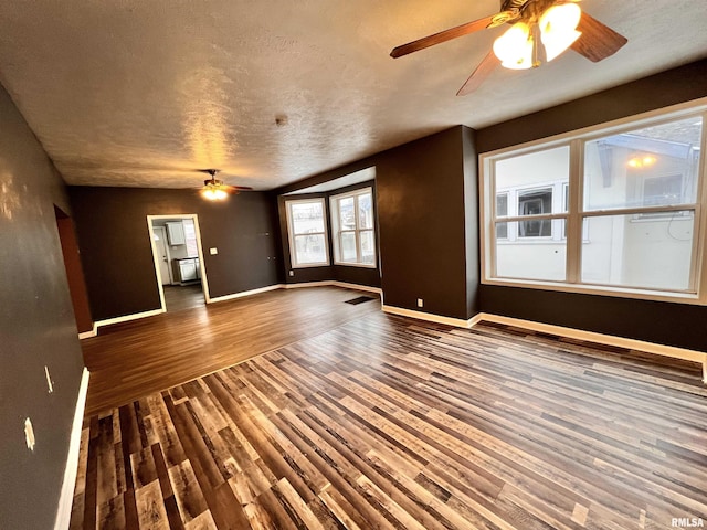 unfurnished living room with ceiling fan, dark wood-type flooring, and a textured ceiling