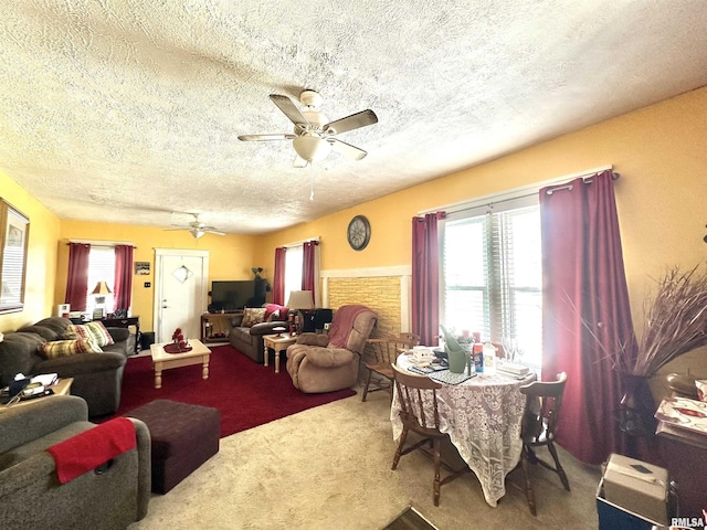 living room featuring a ceiling fan, carpet flooring, a fireplace, and a textured ceiling