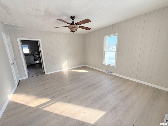 unfurnished room featuring baseboards, light wood finished floors, visible vents, and a healthy amount of sunlight