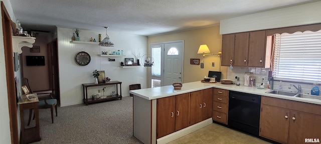 kitchen featuring light countertops, dishwasher, a peninsula, and a sink