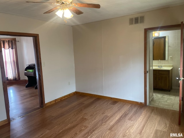 unfurnished bedroom with baseboards, visible vents, a ceiling fan, wood finished floors, and ensuite bathroom