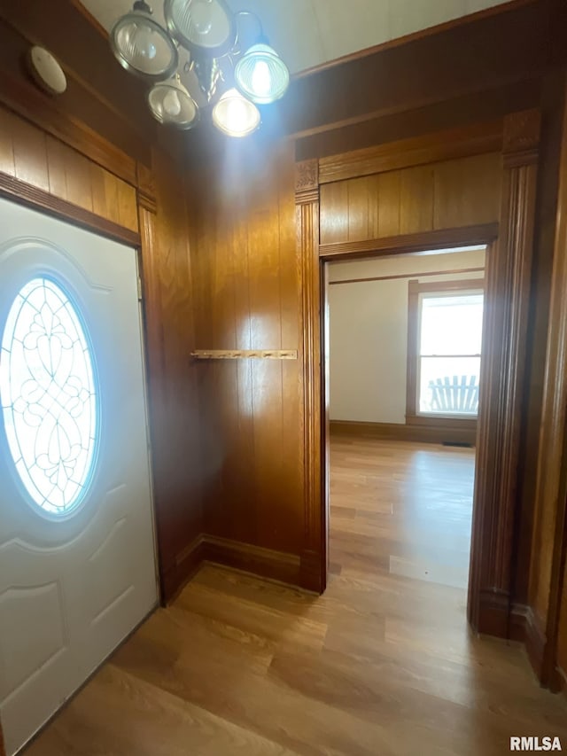 foyer entrance featuring a chandelier, wood finished floors, and wooden walls