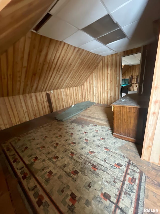 additional living space featuring vaulted ceiling and wood walls