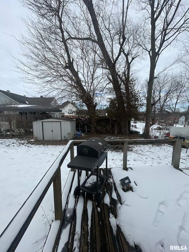 yard covered in snow with an outbuilding, fence, and a storage unit