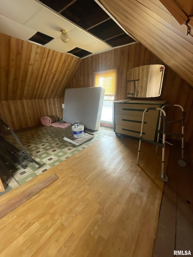 bonus room featuring lofted ceiling, wooden walls, and wood finished floors