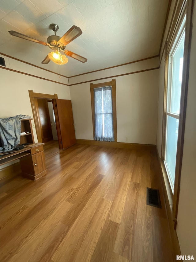 unfurnished bedroom with light wood-type flooring, baseboards, visible vents, and crown molding