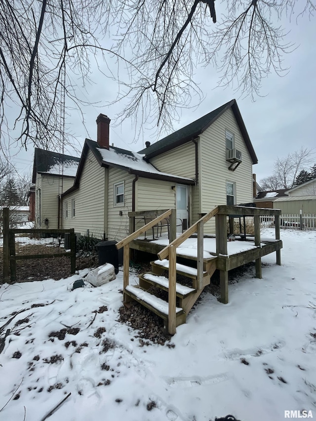 snow covered rear of property with fence and a deck