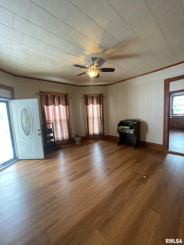 unfurnished living room with ceiling fan, ornamental molding, plenty of natural light, and wood finished floors