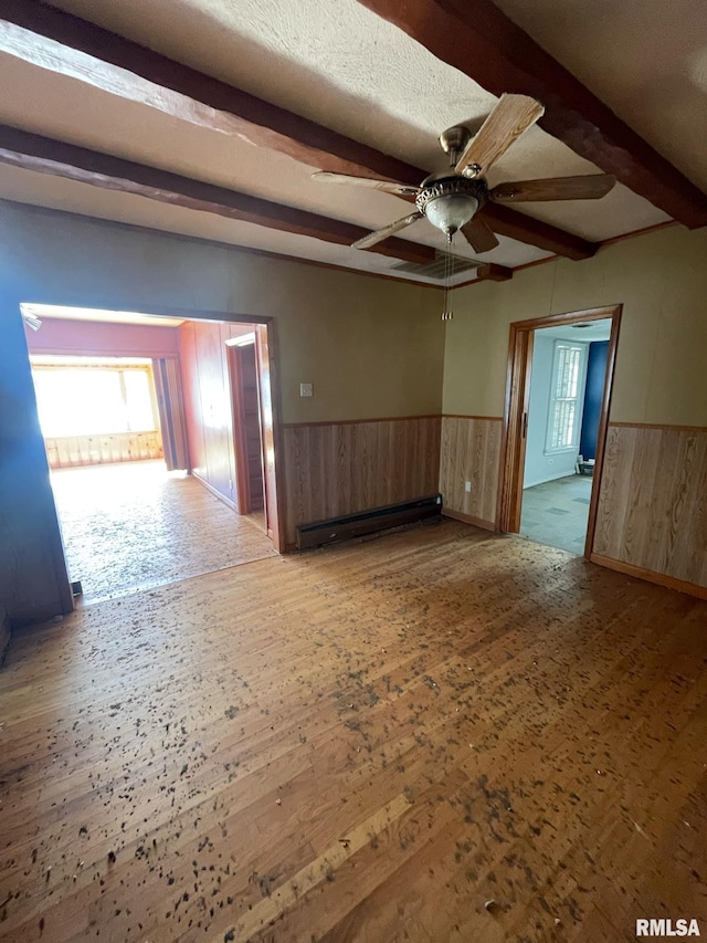 unfurnished room with a wainscoted wall, a baseboard radiator, beamed ceiling, and wood finished floors