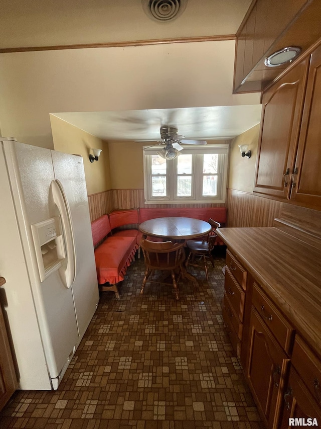 dining area with a wainscoted wall, visible vents, and a ceiling fan