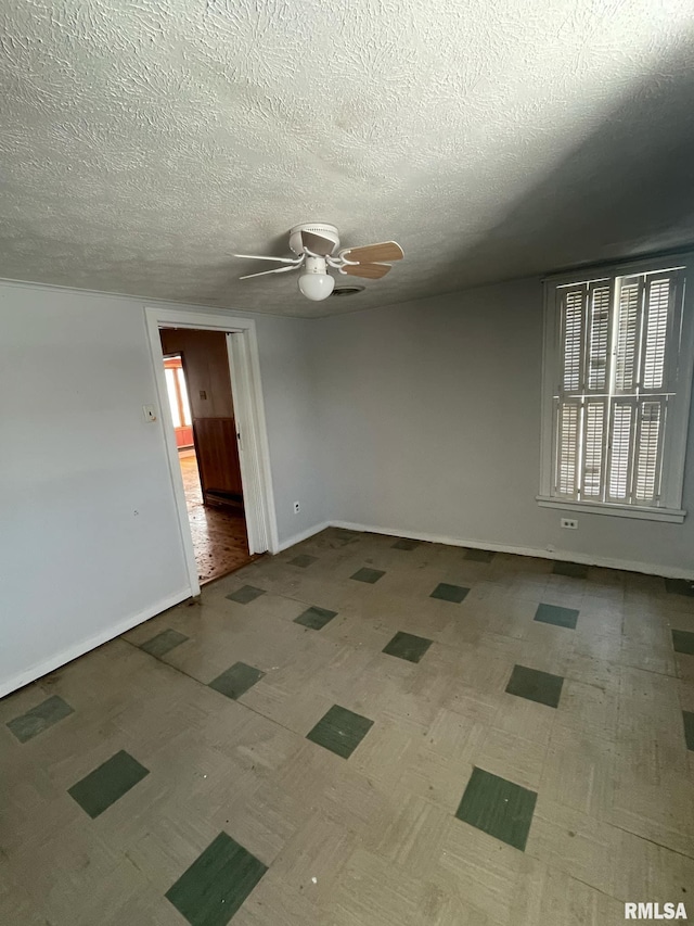 unfurnished room with ceiling fan, a textured ceiling, baseboards, and a wealth of natural light