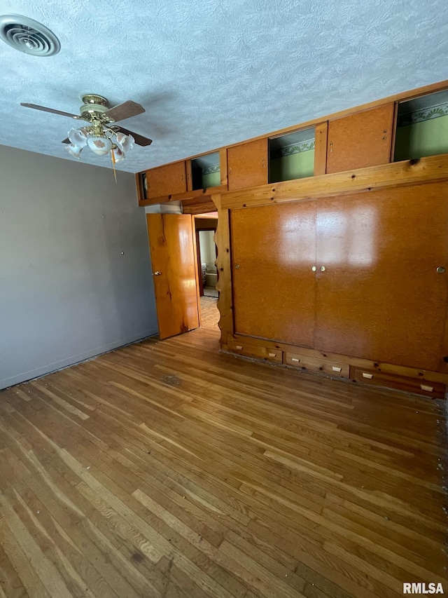 spare room with a ceiling fan, a textured ceiling, visible vents, and dark wood-style flooring