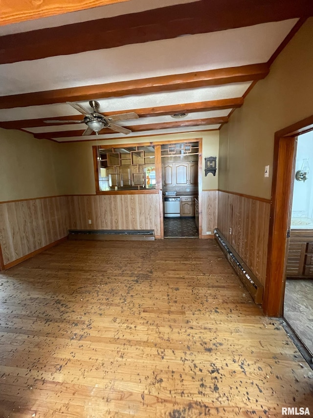 interior space with a baseboard radiator, beam ceiling, wainscoting, and wood walls