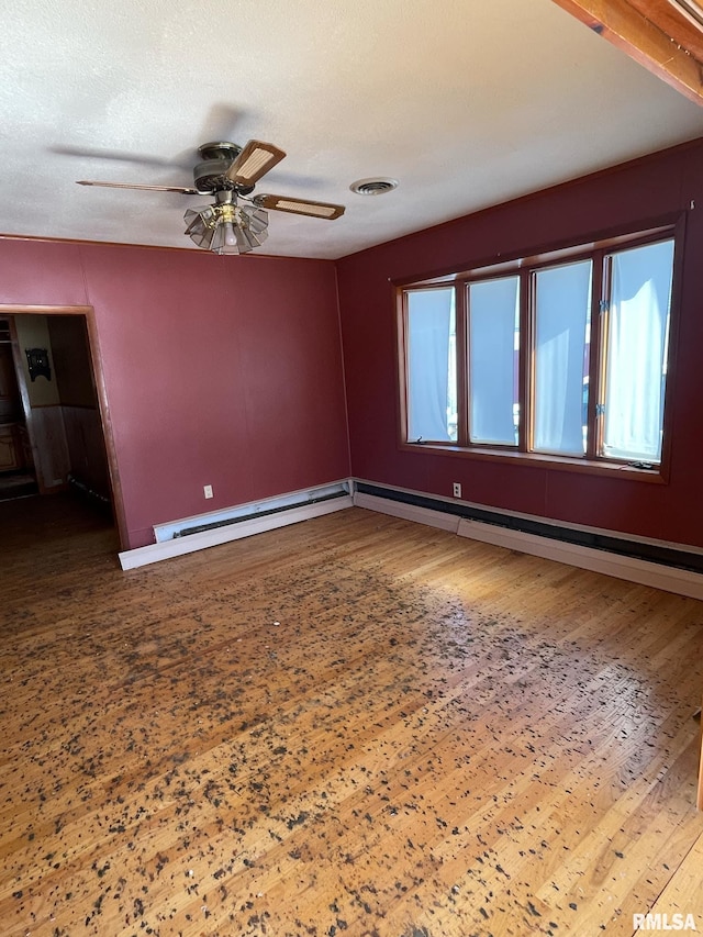 spare room with a baseboard heating unit, visible vents, plenty of natural light, and wood finished floors