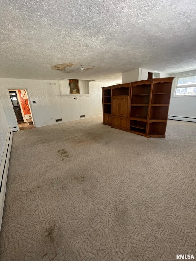 unfurnished room with a baseboard heating unit, carpet, visible vents, and a textured ceiling