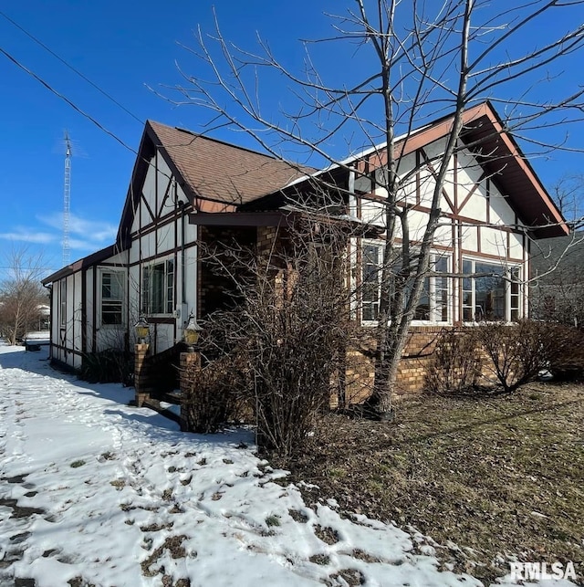 view of snow covered exterior with a shingled roof