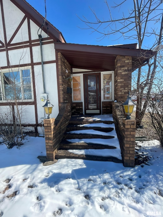 snow covered property entrance with stucco siding