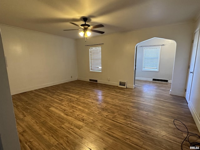 spare room featuring visible vents, arched walkways, and wood finished floors