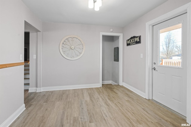 foyer featuring light wood-style flooring, electric panel, and baseboards