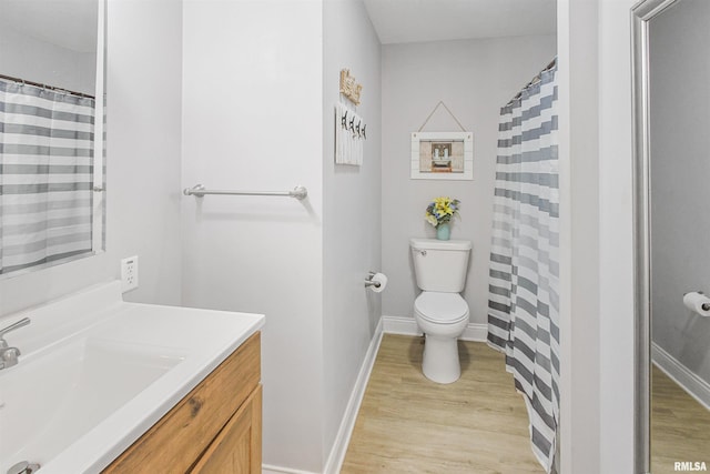 bathroom featuring toilet, baseboards, wood finished floors, and vanity