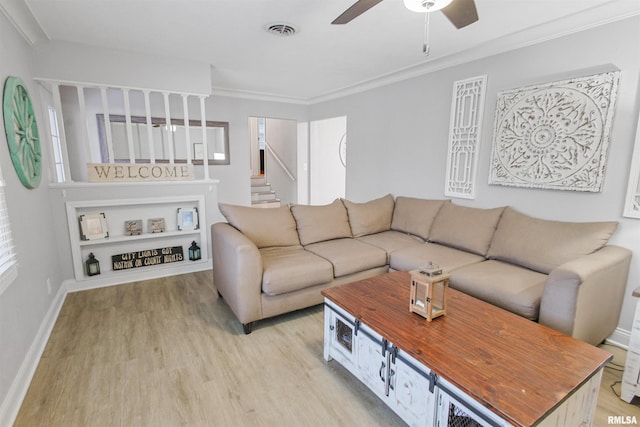 living room featuring light wood-style floors, a ceiling fan, visible vents, and crown molding