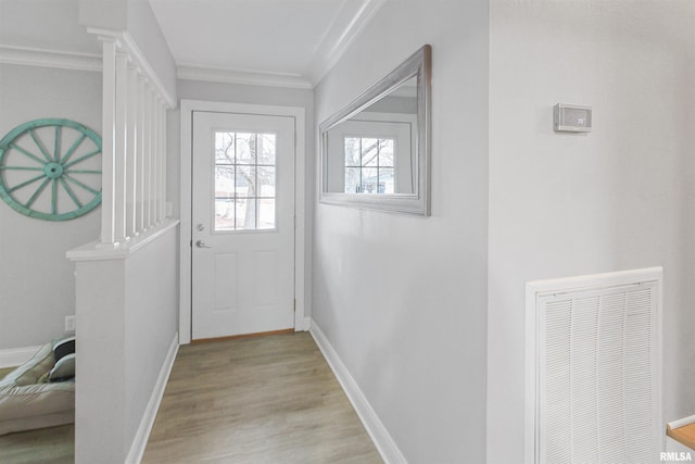 doorway to outside with visible vents, crown molding, light wood-style flooring, and baseboards