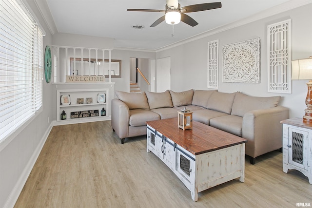 living area with visible vents, baseboards, a ceiling fan, light wood-style flooring, and crown molding