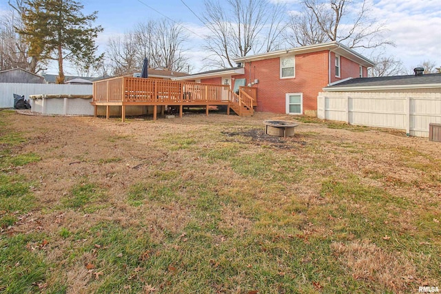 rear view of house featuring a fire pit, brick siding, fence, and a wooden deck