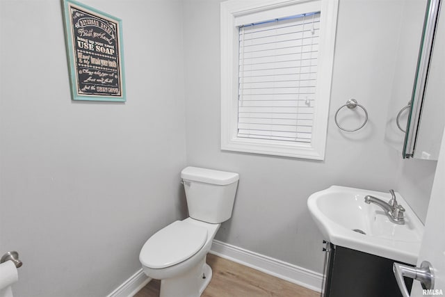 bathroom with toilet, vanity, baseboards, and wood finished floors