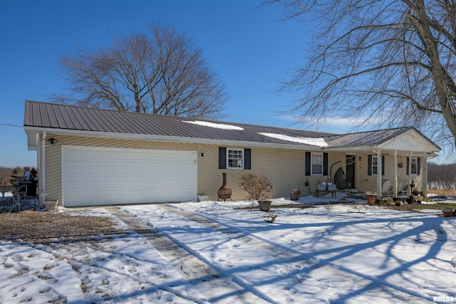 view of front of property featuring metal roof, driveway, covered porch, and an attached garage