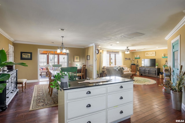 kitchen with dark wood finished floors, a kitchen island, dark countertops, and ornamental molding