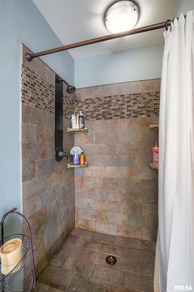 full bath featuring a textured ceiling and tiled shower