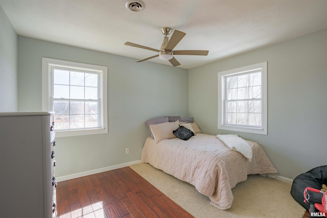 bedroom with a ceiling fan, wood finished floors, baseboards, and visible vents