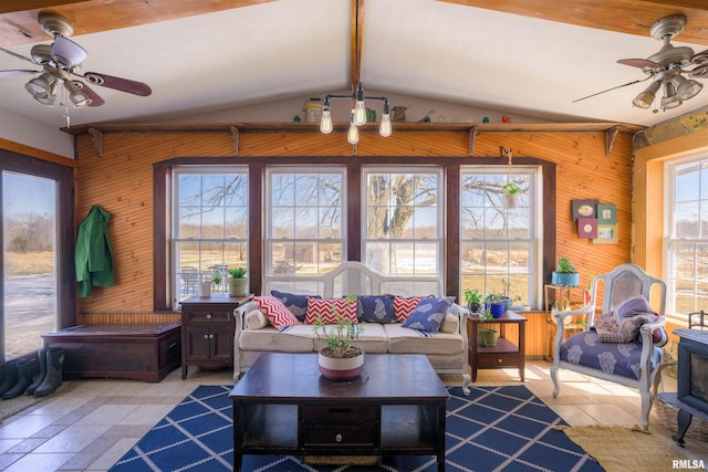 living area featuring wooden walls, vaulted ceiling with beams, and ceiling fan