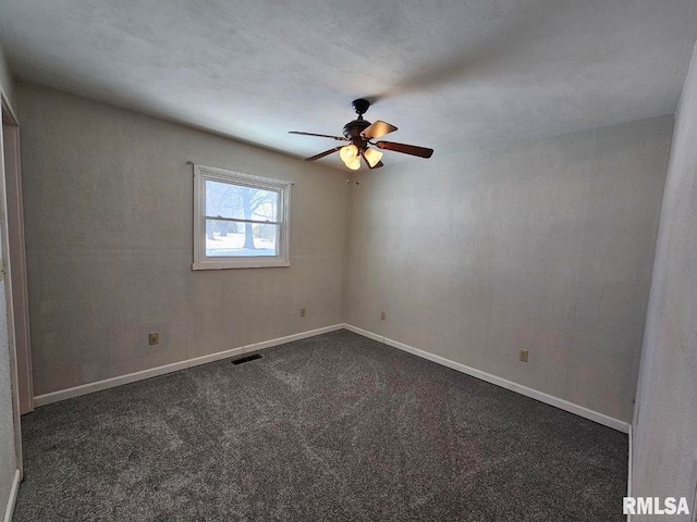 unfurnished room with ceiling fan, dark colored carpet, visible vents, and baseboards