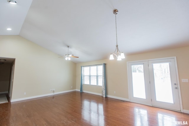 unfurnished living room featuring lofted ceiling, ceiling fan with notable chandelier, wood finished floors, visible vents, and baseboards