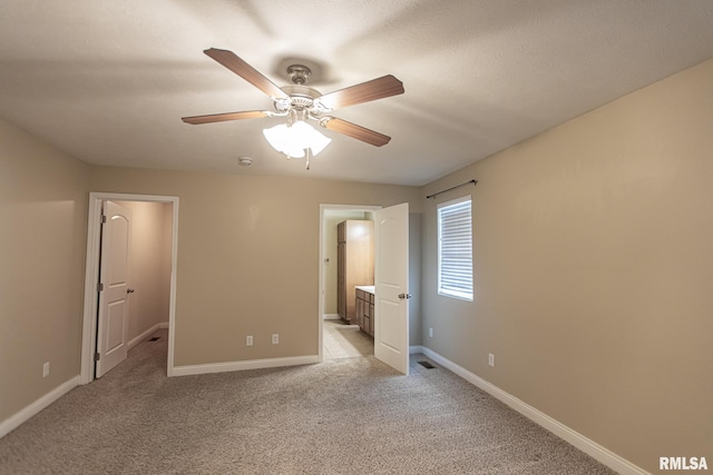 unfurnished bedroom featuring a ceiling fan, light carpet, baseboards, and ensuite bathroom