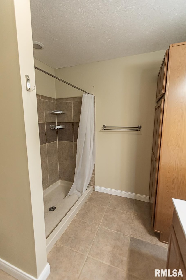 bathroom with baseboards, a stall shower, vanity, and tile patterned floors