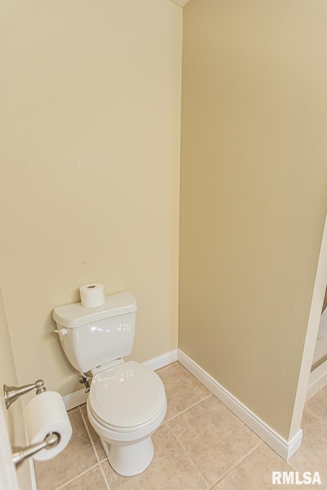 half bathroom featuring tile patterned flooring, baseboards, and toilet